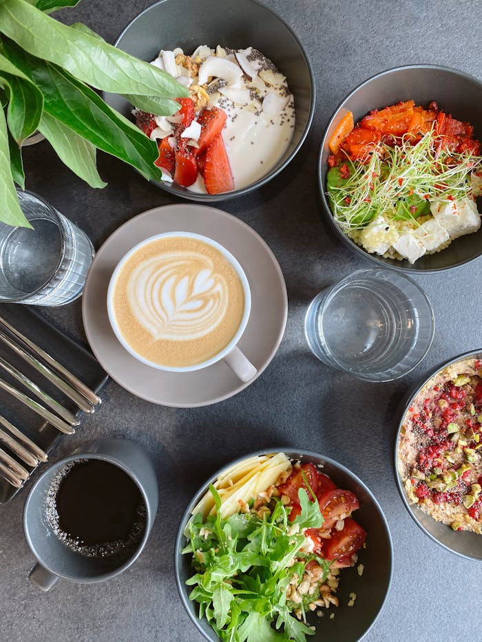 Top view of a vibrant breakfast assortment featuring coffee art, fresh salads, and desserts.